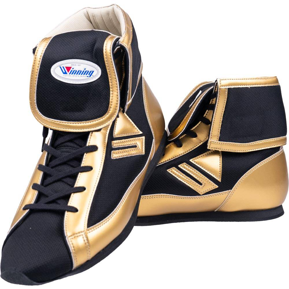 A pair of Winning boxing shoes in a black and gold colorway, featuring a high-top design and the Winning logo on the tongue, displayed on a white background.