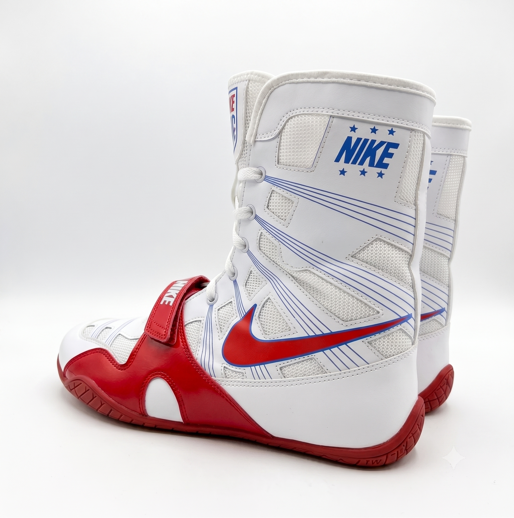 A pair of white high-top athletic boxing shoes with red and blue Nike branding, shown from a three-quarter angle on a light gray studio background.